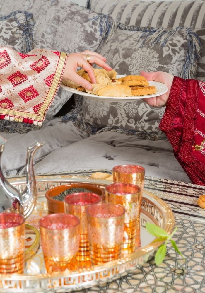 moroccan tea party woman serving moroccan cookies and tea to a guest